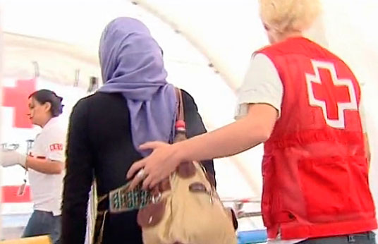 Una voluntaria de Cruz Roja ayuda a una persona refugiada.